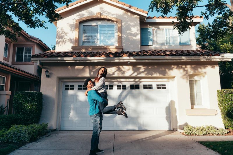 Joyful couple celebrating in front of their new home on a sunny day.
