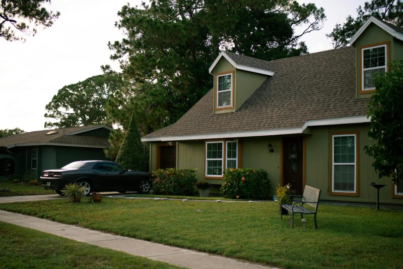 Home 3 Beautiful suburban home with a green lawn, parked car, and clear blue sky.