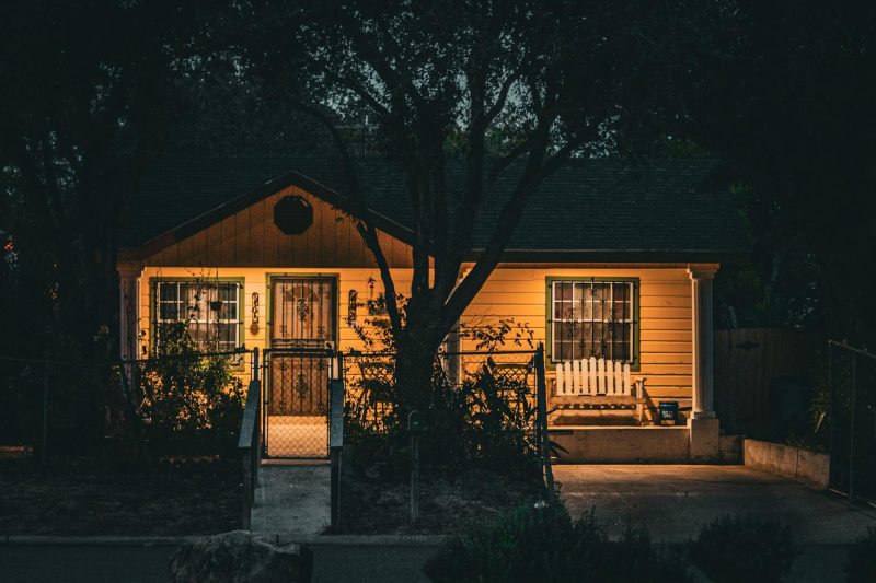 Cozy yellow house warmly illuminated at night, nestled among trees in a Texas setting.
