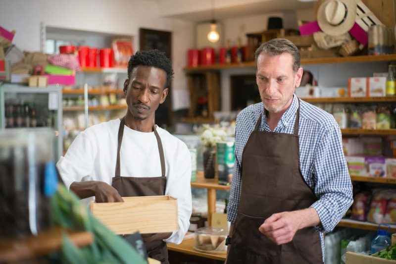 Two men arranging products on shelves in a warm, inviting grocery store.