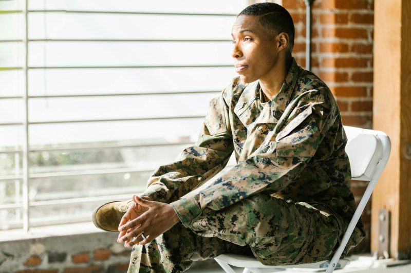 US veteran in uniform seated indoors, looking thoughtfully, with a calm and reflective expression.