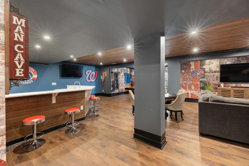 Modern man cave featuring a sleek bar, sports decor, and comfortable seating arrangements.