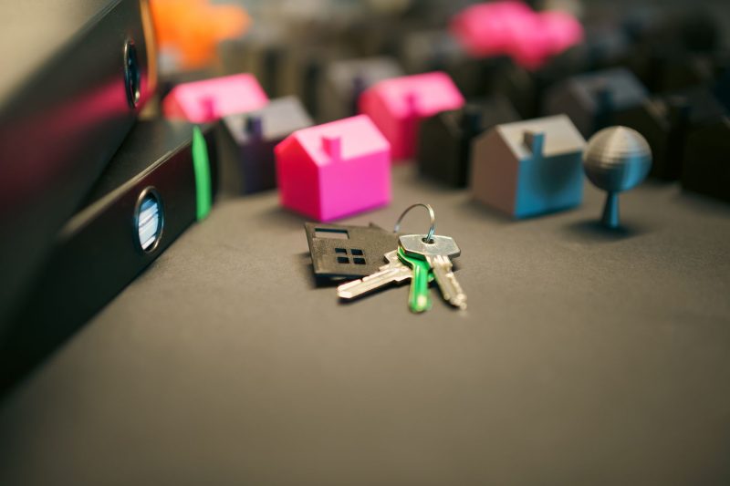 Miniature model houses and American keys arranged on a desk, depicting real estate investment.