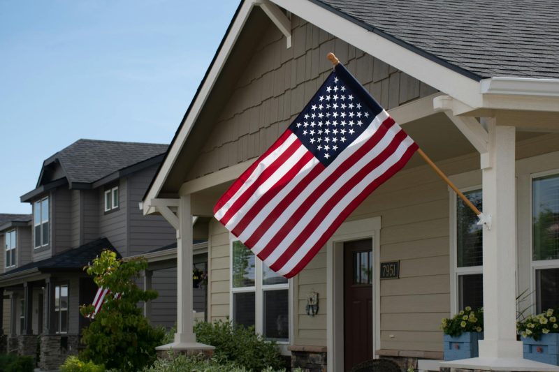 Home 3 A vibrant American flag flutters outside a stylish suburban house under clear daylight.