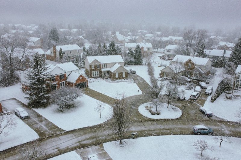Aerial view of a tranquil suburban neighborhood covered in a blanket of snow on a winter day.